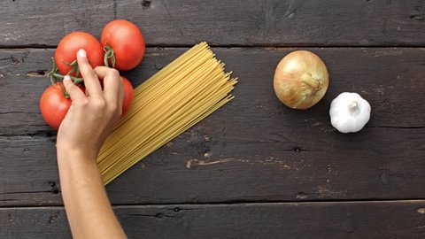 4k Time lapse of woman hands placing ingredients of a recipe of vegetarian pasta on kitchen counter table. 