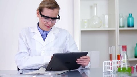 Happy female scientist working on tablet computer in laboratory