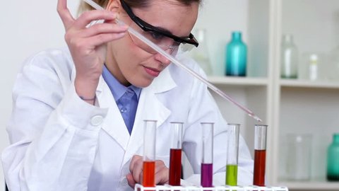 Scientist using pipette to add substance to test tubes with chemicals