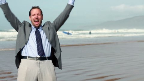 Excited businessman screaming and raising hands to the sky by the sea, slow motion Video stock