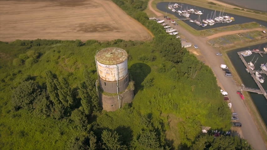 Old water tower in lush green bushes pan around. Aerial shot