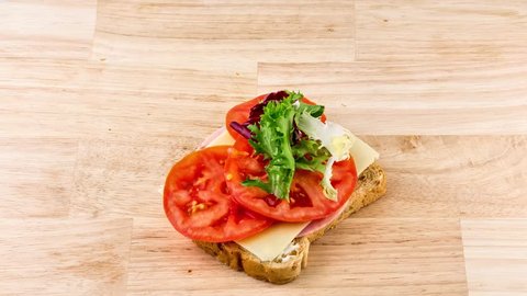 making sandwich bread with tomato, ham, cheese and salad stop motion. preparing snack. stop motion, top view. 4K