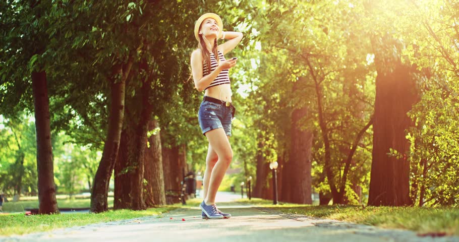 Attractive young woman listening to music on the player and dancing in the park alley. Slow Motion, 4K. Happy young girl having fun in the park, dancing, singing, enjoying nature and life. Lens flare. | Shutterstock HD Video #19183828