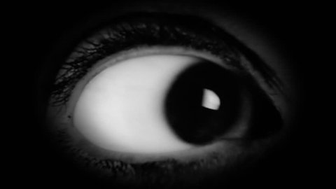 The big eye of a woman, looking in camera, scared. Film-noir style. Detail macro shot.
