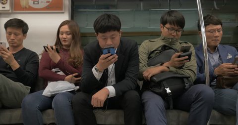 SEOUL, SOUTH KOREA - OCTOBER 22, 2015: Korean commuters riding in underground train and entertaining themselves with smart phones