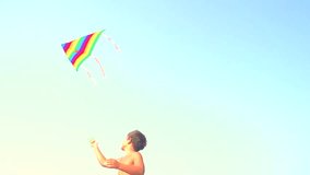 Little boy flying a kite on the beach. Happy kid playing with flying kite. Summer vacation concept. Slow motion 240 fps. Full HD 1080p. High speed camera