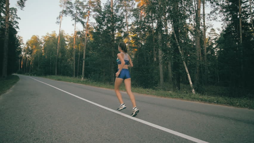 Athletic youg woman Jogging in a park. Stedycam shot.