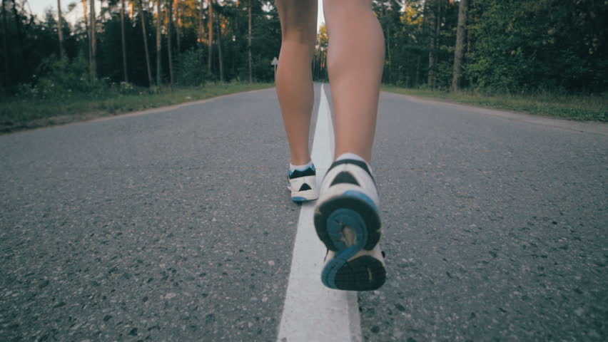 Athletic youg woman Jogging in a park. Close up of running shoes and legs in action. Stedycam shot.