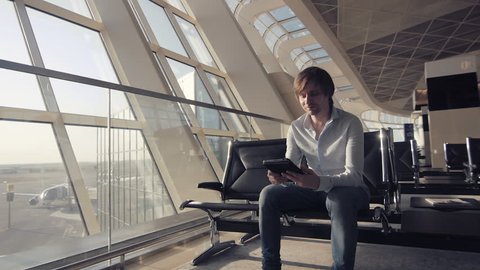 handsome smiling man holding tablet and working at the airport, technology, travel and modern life concept