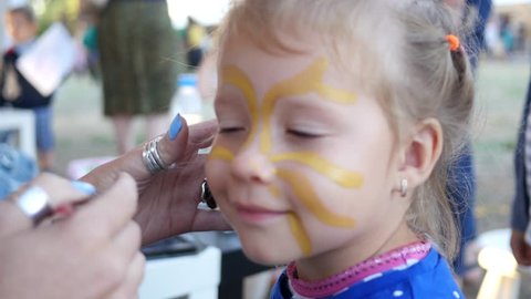 Painting body art on a face of little cute child girl - happy childhood portrait