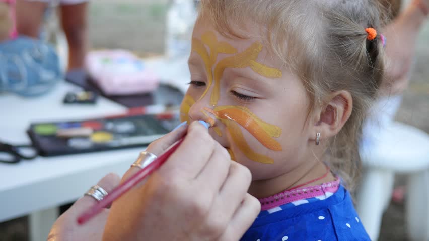 Painting body art on a face of little cute child girl - happy childhood portrait