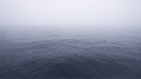 Foggy morning at sea with total white blank sky, view form a moving cruise ship