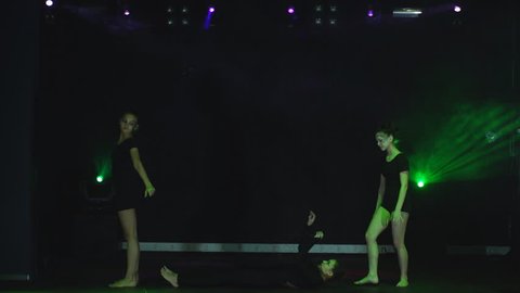 three girls gymnasts perform acrobatic moves
