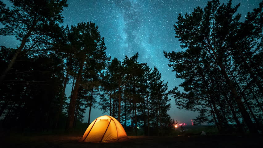 Moving milky way above tent at night in a forest. time lapse