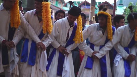MANALI, H.P. INDIA - MAY 16, 2016- Line of men decorated in traditional clothing dance in line during a festival, side shot, pan, slow motion, in Manali, India