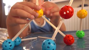 Little boy playing with colorful plastic construction set. Molecule models. 4K close up video