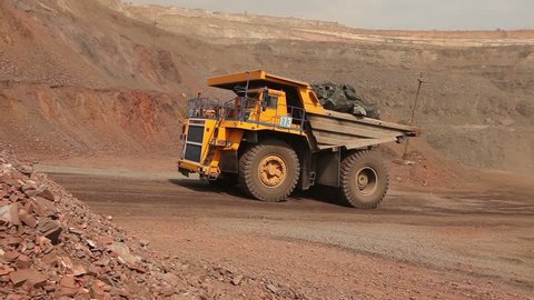 big yellow truck in a career of iron ore mining, delivery by the motor transport of iron ore from a pit, pit iron ore,