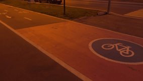 Cyclist and runner passing by on urban bike path at night. 4K video