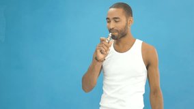 Happy cheerful african man in white t-shirt smokes a vape e-cigarette