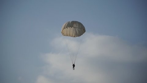 paratrooper landed on the grass and blue sky with clouds, white parachute