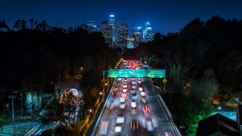 Beautiful view of Los Angeles Skyline from 110 Freeway at dusk. Close up. Traffic passing by. Timelapse. California, United States.