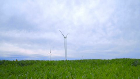 Wind farm in green field. WInd turbines farm. Wind technology. Green energy concept. Wind generators on farm field generating electricity