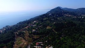 Flying over Corfu village countryside ocean sea coast Greece. Aerial travel 4k video. Villas hills houses trees