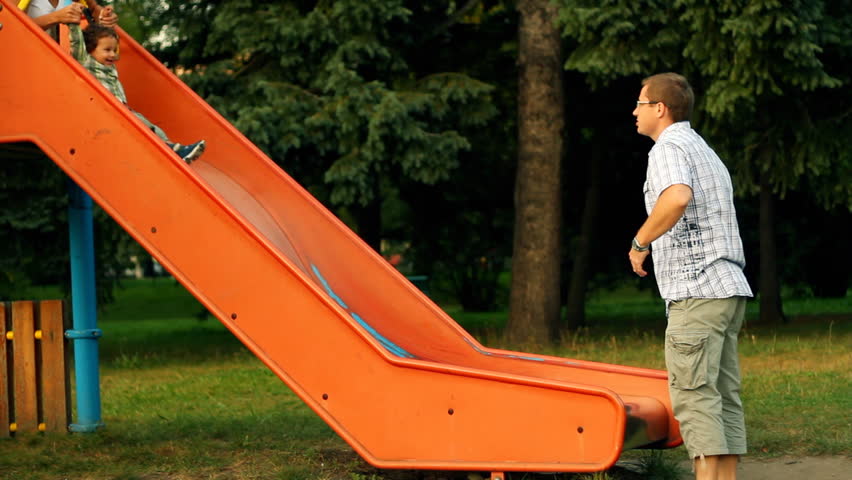 Young parents with their son on slide in the park