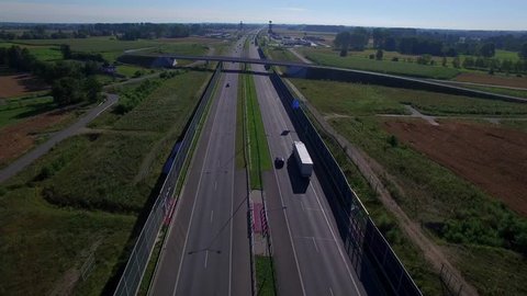 Fly up over overpass bridge at highway with cars lorry trucks moving both directions 4K HD. Cars moving on road vehicles traffic under bridge picturesque top view landscape Poland East Europe