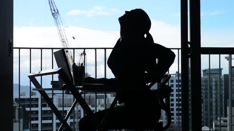 Silhouette of Young woman (age 30-40) having back pain while working at desk in office. Woman work healthcare lifestyle concept. Real people. copy space