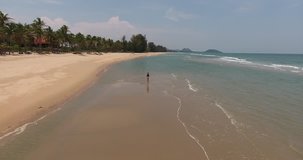 Aerial shooting from flying drone of woman wanderer is walking on seashore during her unforgettable summer vacation on Bali. Video with for presentation of high quality resolution of display