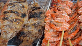 Grilled seafood. including shrimp kabobs and skewered. salt encrusted. whole tilapia. for sale at an outdoor public market in Thailand. 4k UltraHD footage