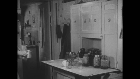 UNITED STATES, 1940s: Lady prepares pickle jars. Man screws jar lid for lady.