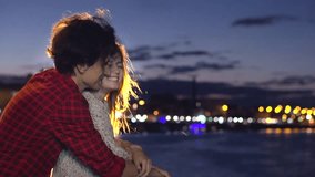 Beautiful happy young couple dating, looking on beautiful night city, hugging and kissing together. Girlfriend and boyfriend walking on night streets, enjoying night view. Full HD 1080p