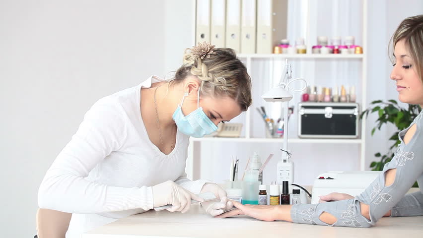 Young woman in respirator doing artificial nails 
