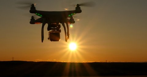 Aerial drone aircraft taking aerial footage at sunset