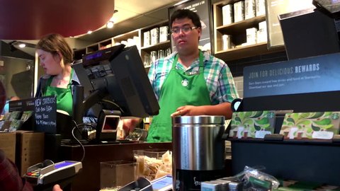Coquitlam, BC, Canada - September 02, 2016 : Customer buying coffee and paying by apple pay at Starbucks with 4k resolution.