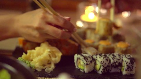 Happy couple eating sushi rolls in japan restaurant, sushi bar. Dinner. People eating Japanese food, diet, dieting. Slow motion 240 fps, high speed camera shot. Full HD 1080p