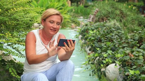 Middle aged, happy woman sending a text messaging with smartp hone