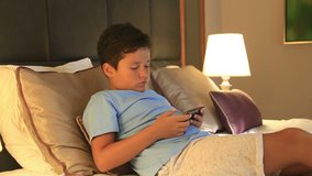 Child lying on a bed and using smart phone. Smart phone addiction