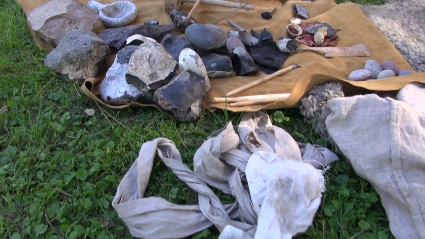 Tools and weapons made of flint and wood placed on fur in historic fair festival

