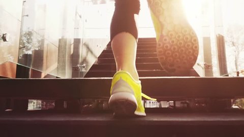 Runner Woman Feet Jogging up Stairs, Close Up, Lens Flare. SLOW MOTION 120 fps Steadicam STABILIZED shot. Athletic Healthy Female in Bearfoot Sports Shoes Running Up the Modern Sunny Glass Stairs. 