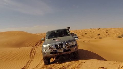 SAHARA DESERT, TUNISIA - CIRCA OCTOBER 2015:  two off road cars drive down a  dune in the Sahara desert.