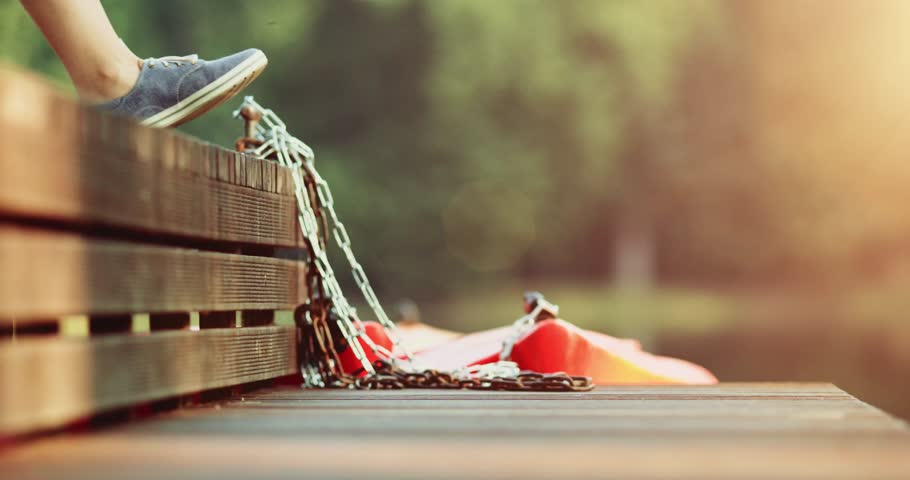 Female feet in sneakers gumshoes walking and posing on a wooden jetty by the lake close up. Woman