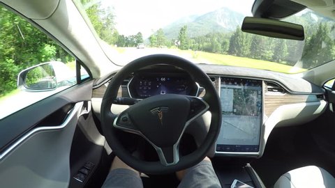 AUTONOMOUS TESLA CAR, JULY 2017:  Unrecognizable person self driving autonomous electric car, navigating and steering without driver on winding countryside road. Vehicles coming on the opposite lane Toimituksellinen arkistovideo