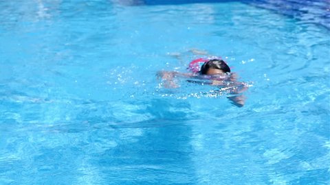 Little girl with goggles swimming under water in pool