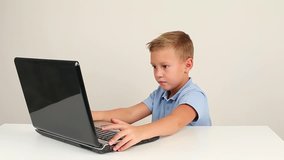 Cute teen boy working on laptop computer or watching video in internet