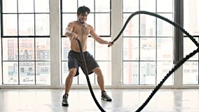 Athletic Male Working Out Using Battle Ropes. High-intensity interval training. Slow Motion.