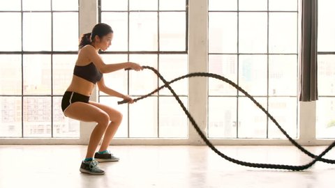 Athletic Female Working Out Using Battle Ropes. High-intensity interval training. Slow Motion.