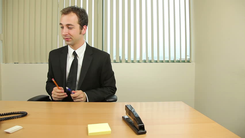 Dolly shot of a bored businessman goofing around at work.